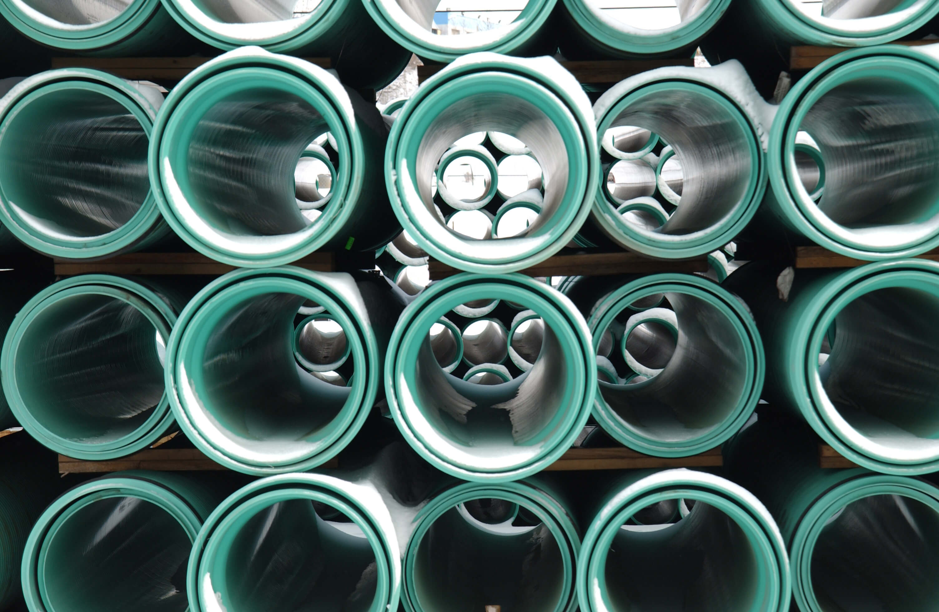 Many green plastic pipes in a stack.
